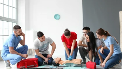 Female first aid trainer performing CPR on manikin